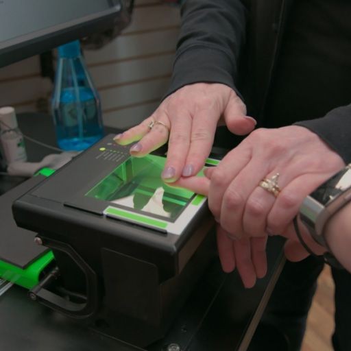 View of a fingerprint technician fingerprinting an applicant on a live scan scanner